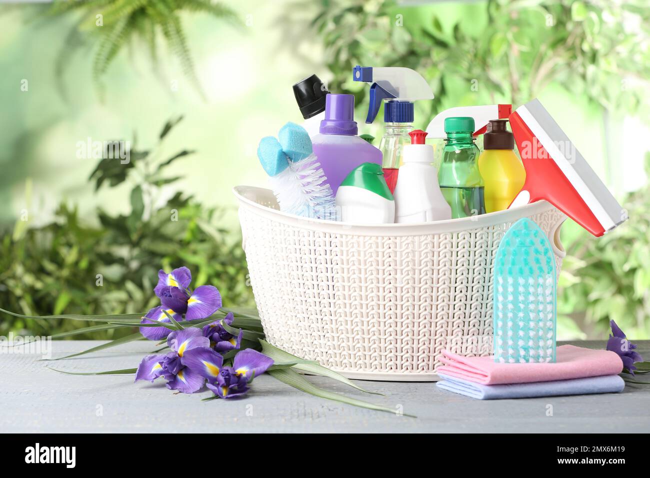 Spring flowers and cleaning supplies on light wooden table Stock Photo