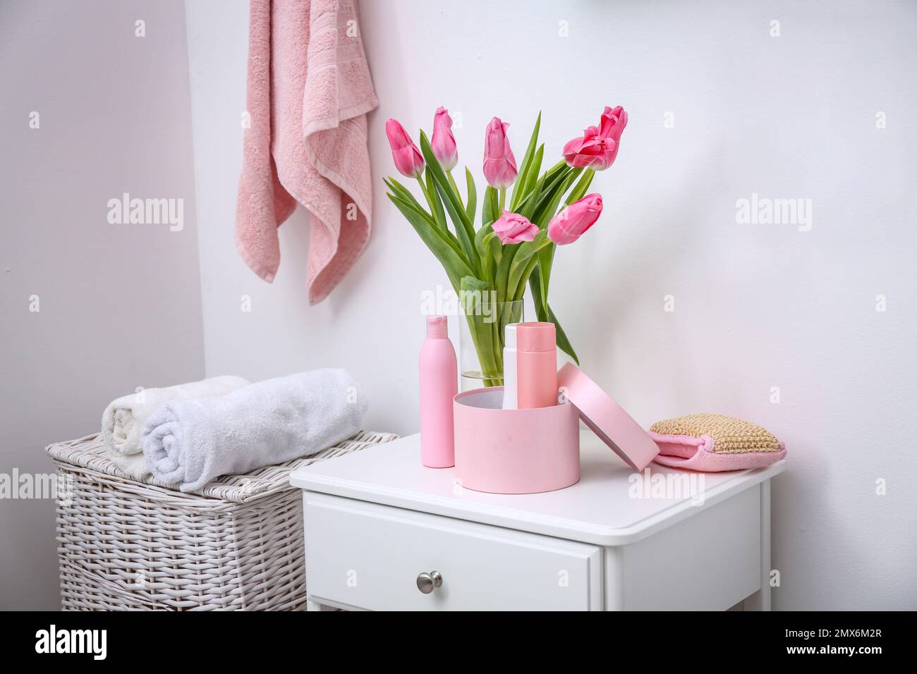 Fresh tulips and toiletries on cabinet in bathroom Stock Photo