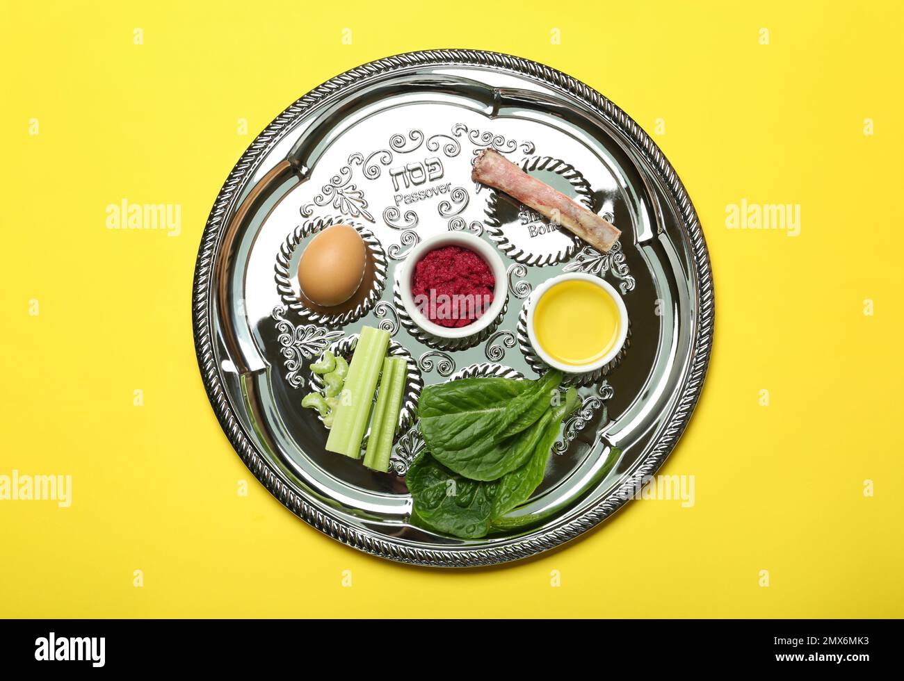 Passover Seder plate (keara) with symbolic meal on yellow background