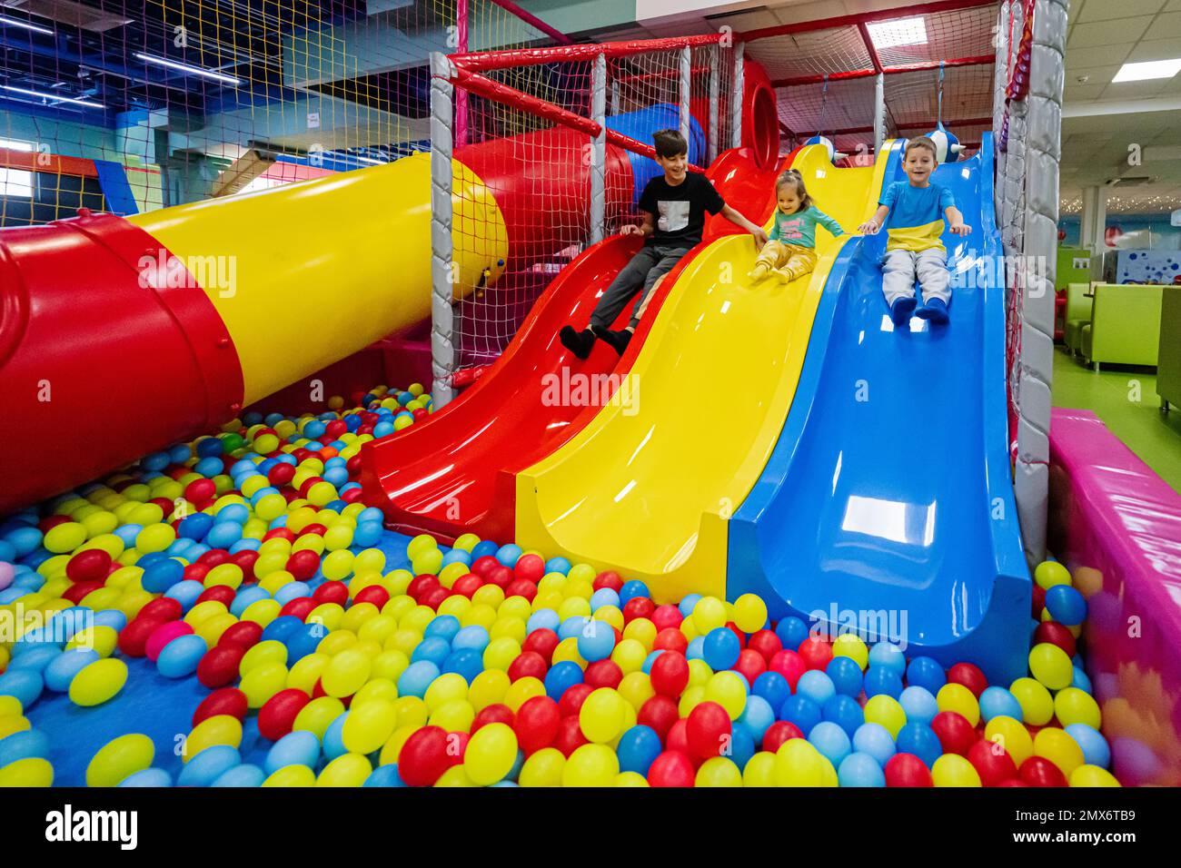 Happy kids playing at indoor play center playground. Children slides in colored slide into balls