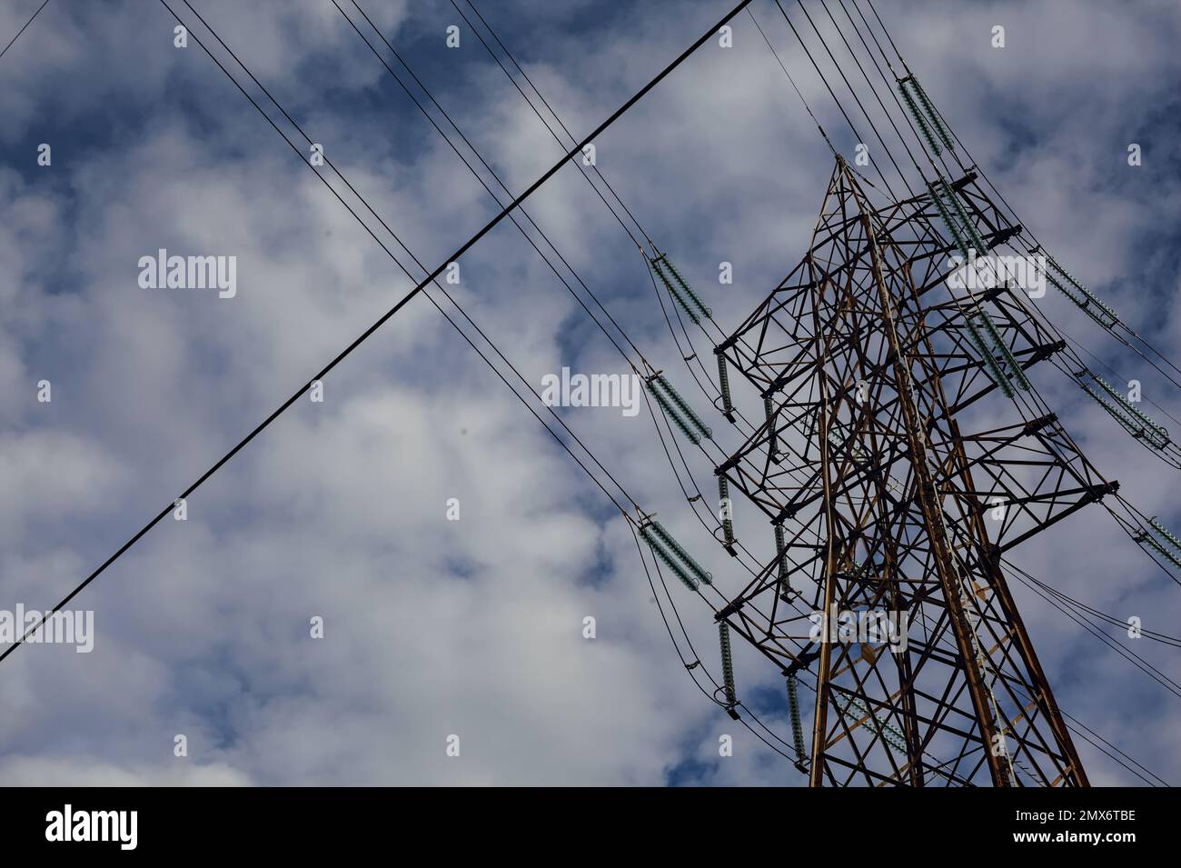 Power lines and a pylon with a cloudy sky as background Stock Photo - Alamy
