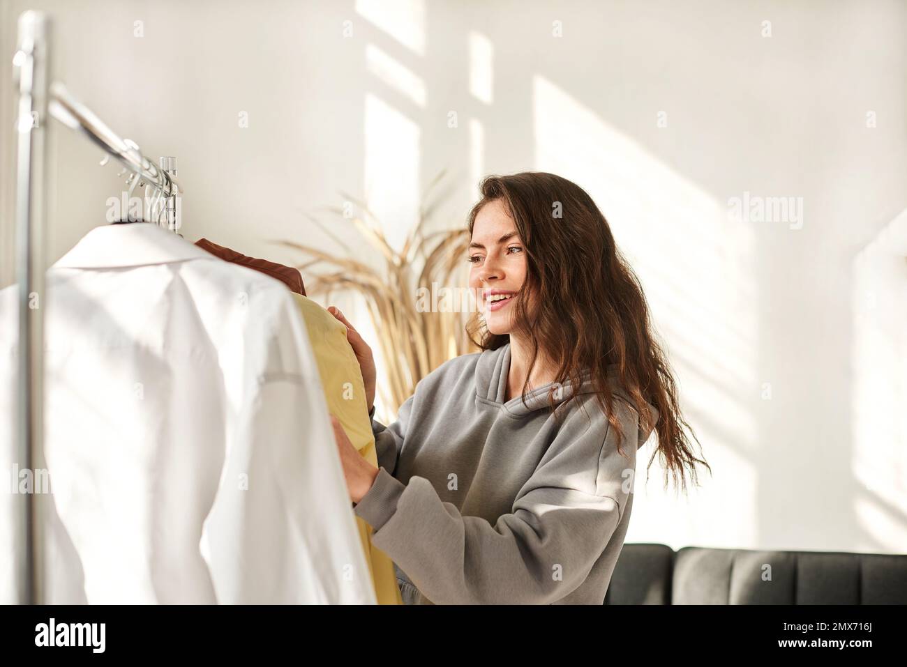 Second hand used clothes on hangers. woman chooses clothes for second hand Stock Photo