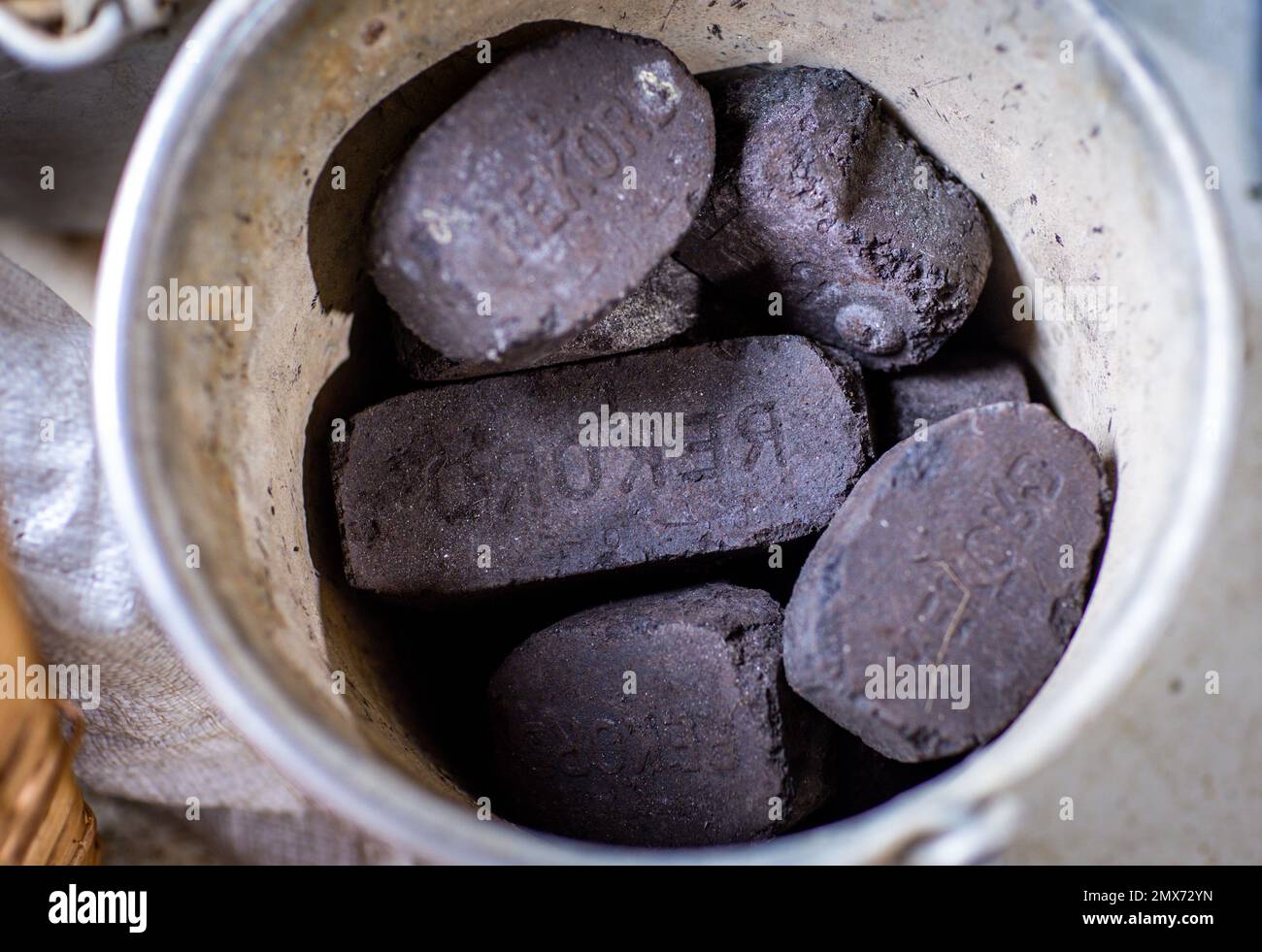 PRODUCTION - 26 January 2023, Mecklenburg-Western Pomerania, Teplitz: Coal briquettes for heating are in a bucket next to a stove. Photo: Jens Büttner/dpa Stock Photo