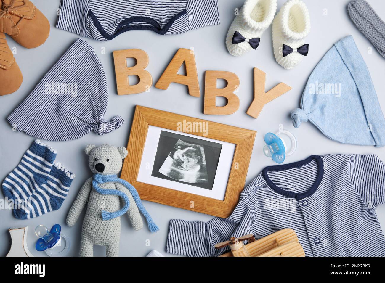 Flat lay composition with child's clothes, ultrasound photo and word Baby on light background Stock Photo