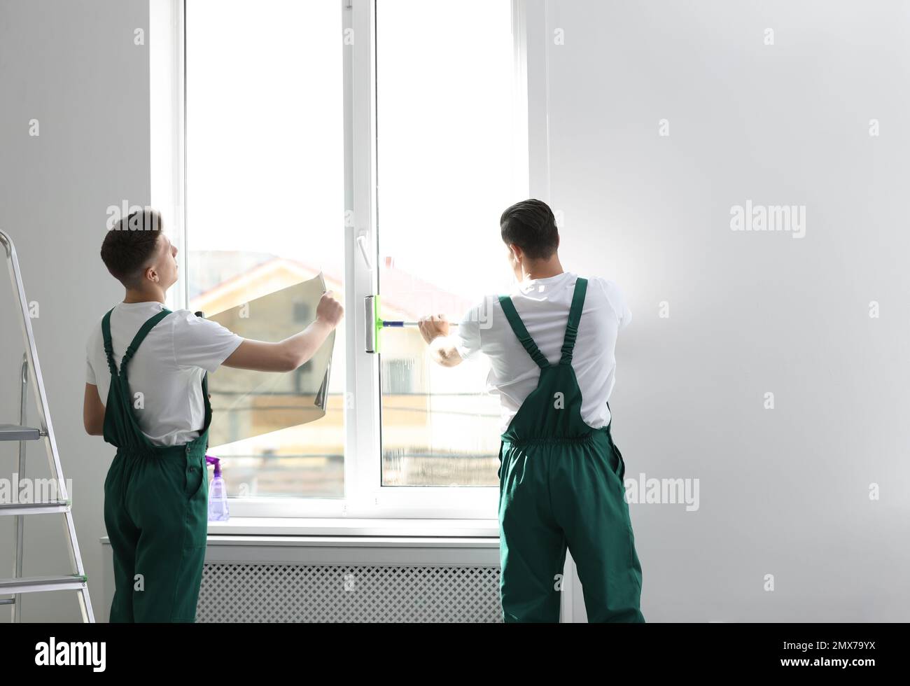 Professional workers tinting window with foil indoors Stock Photo