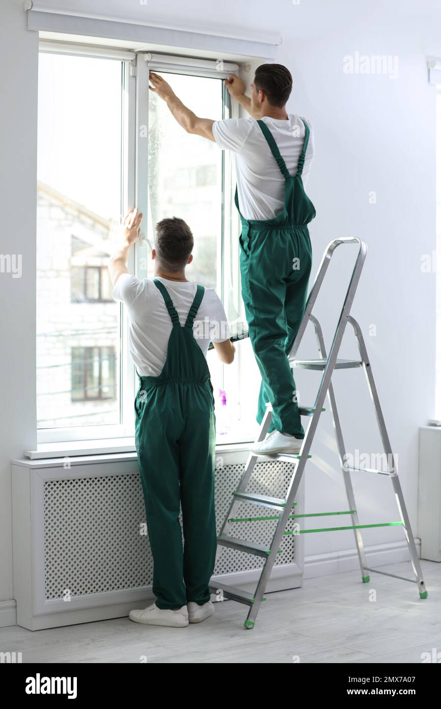 Professional workers tinting window with foil indoors Stock Photo