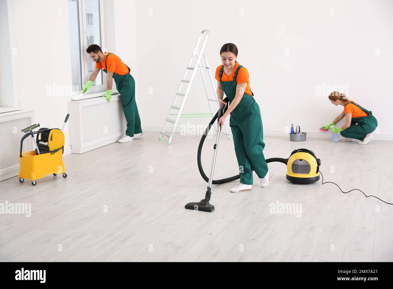 Team of professional janitors in uniforms cleaning room Stock Photo