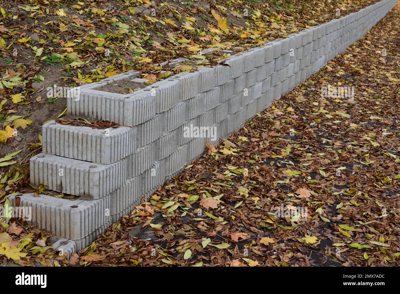 A retaining wall made of concrete elements protects the roadway and