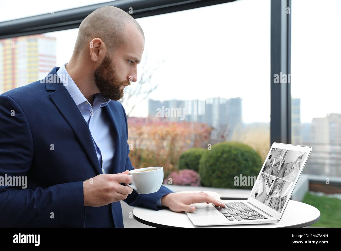 Man monitoring modern cctv cameras on laptop indoors. Home security