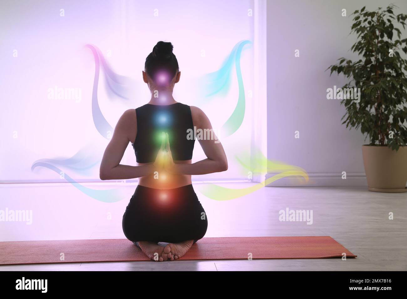 Young woman with chakra points practicing yoga in studio, back view. Healing energy Stock Photo