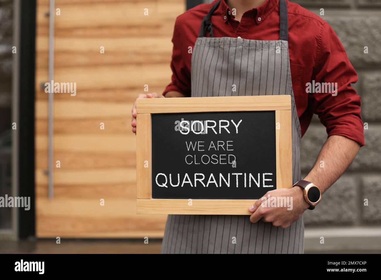 Business owner holding sign with text SORRY WE ARE CLOSED QUARANTINE near his cafe, closeup Stock Photo