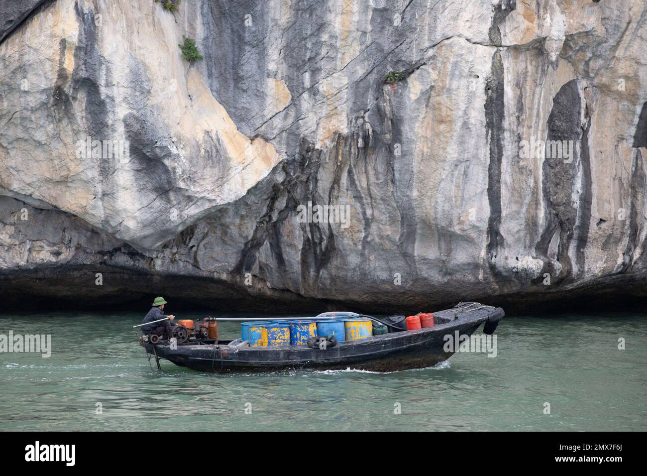 A small boat against the giant rock landscape - Ha Long Bay , Vietnam Stock Photo