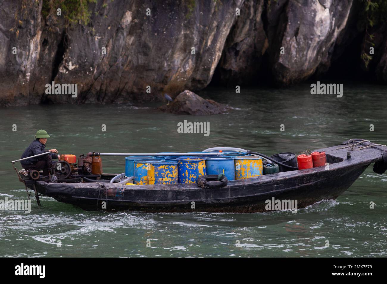 A small boat against the giant rock landscape - Ha Long Bay , Vietnam Stock Photo