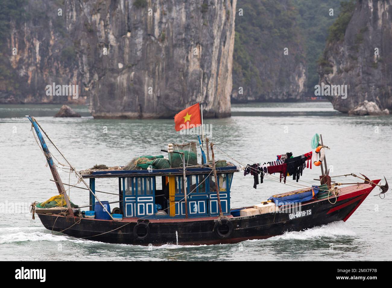 A small boat against the giant rock landscape - Ha Long Bay , Vietnam Stock Photo