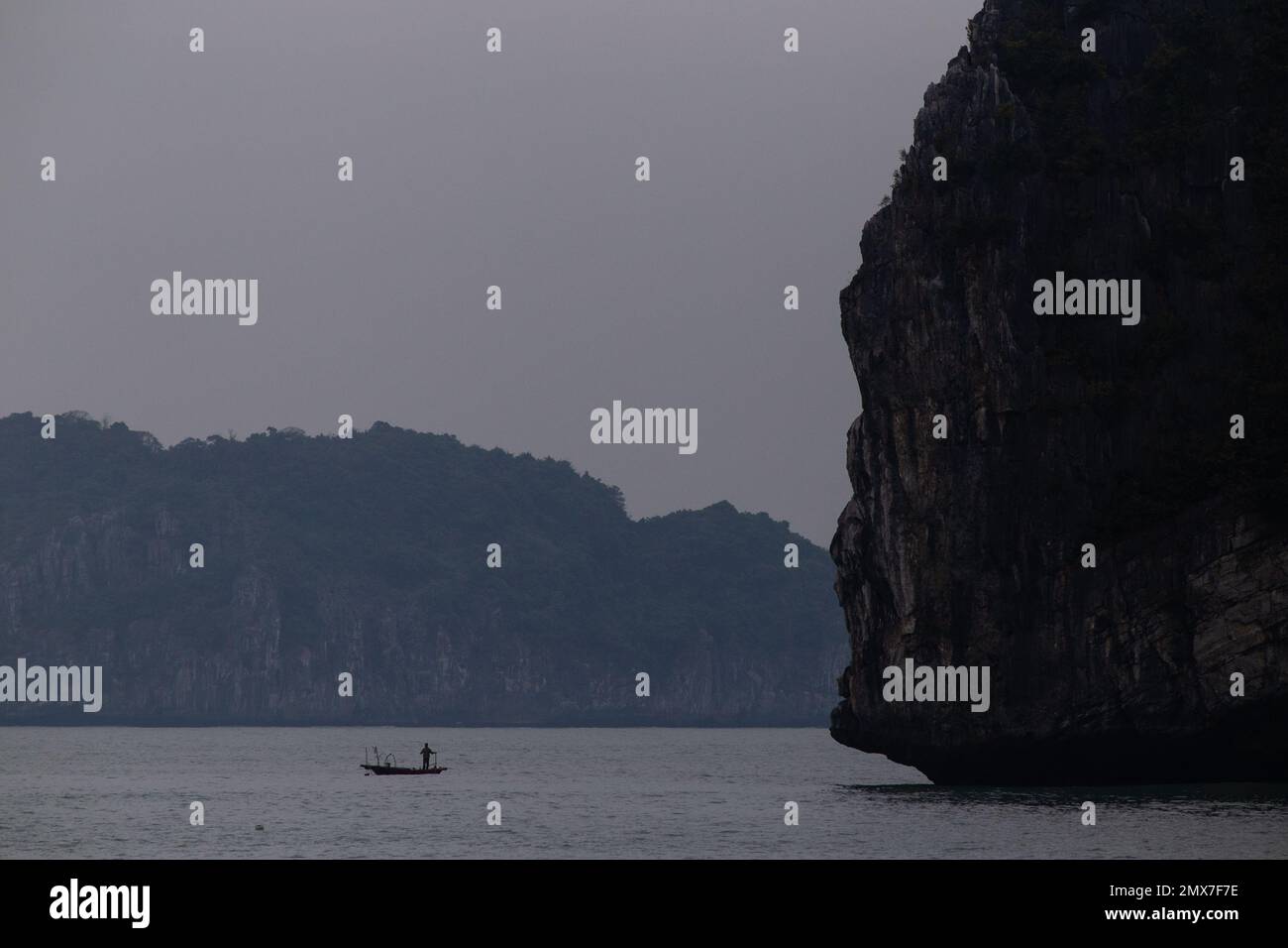 A small boat against the giant rock landscape - Ha Long Bay , Vietnam Stock Photo