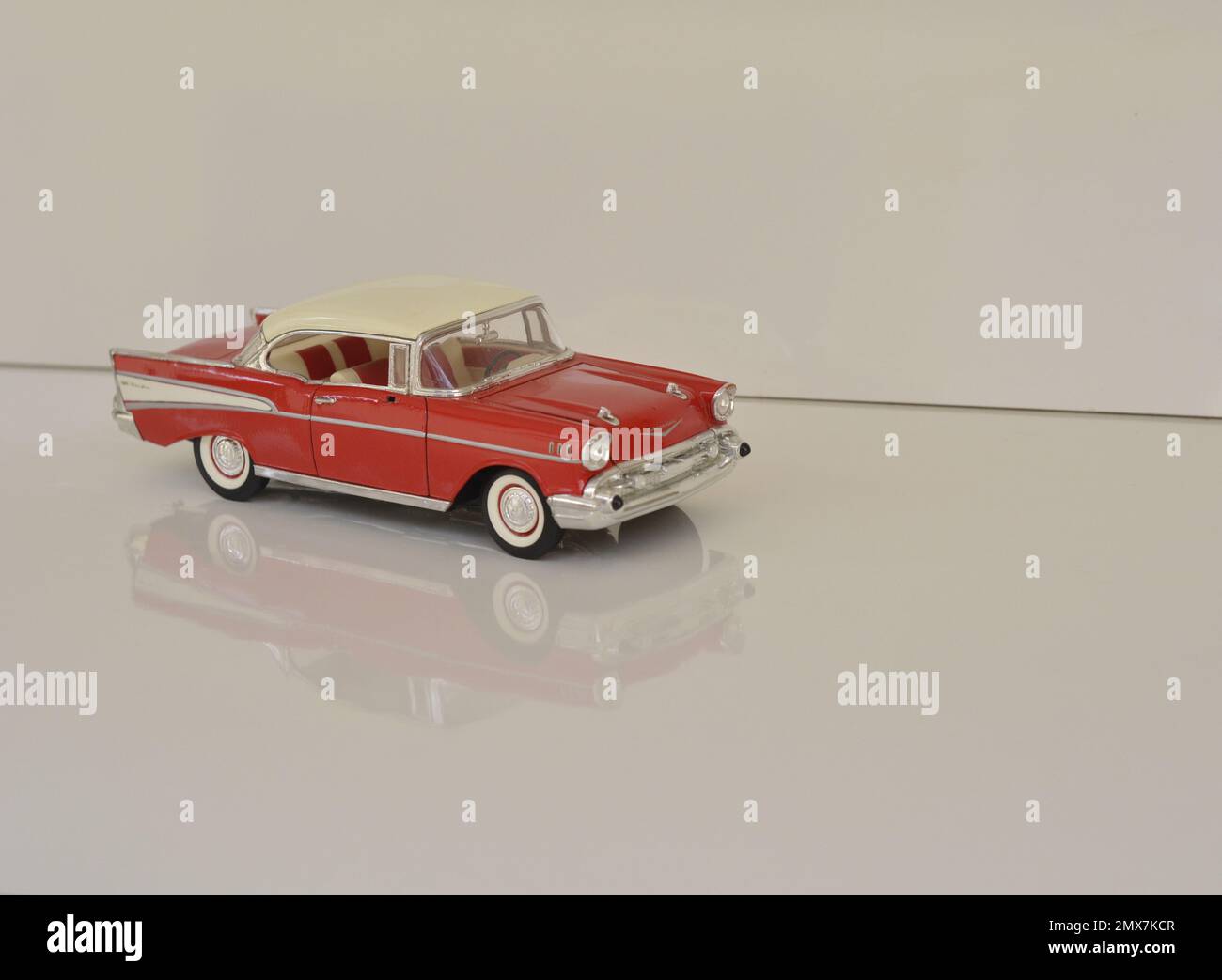 Miniature car of famous brand in red and white color. White background and base. negative space