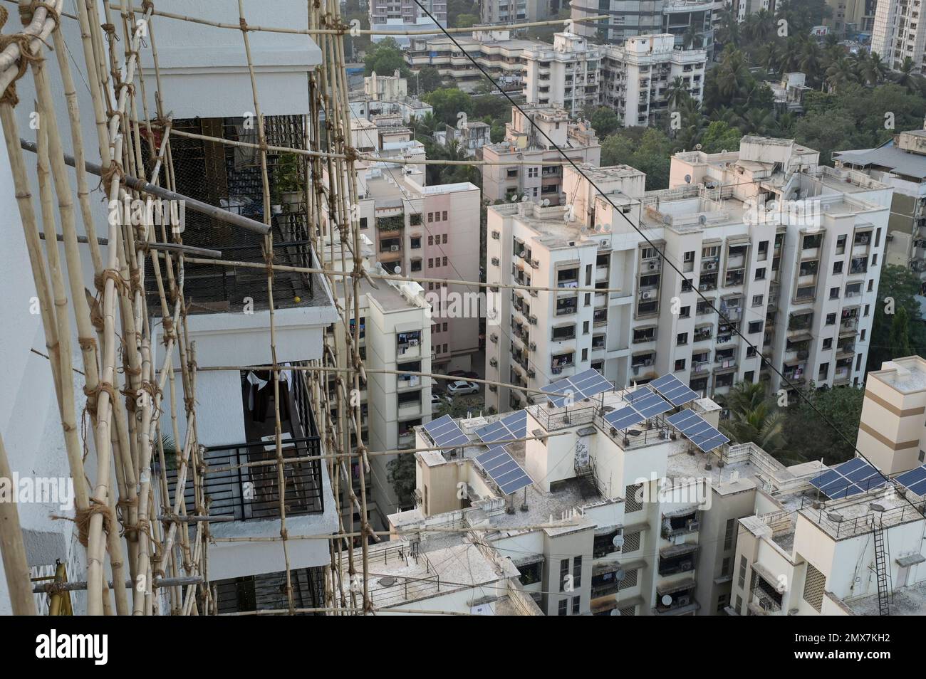 INDIA, Mumbai, apartment tower under renovation, bamboo scaffold, solar panel on roof / INDIEN, Mumbai, Wohnhaus mit Baugerüst aus Bambus, Solar Module auf Dach Stock Photo