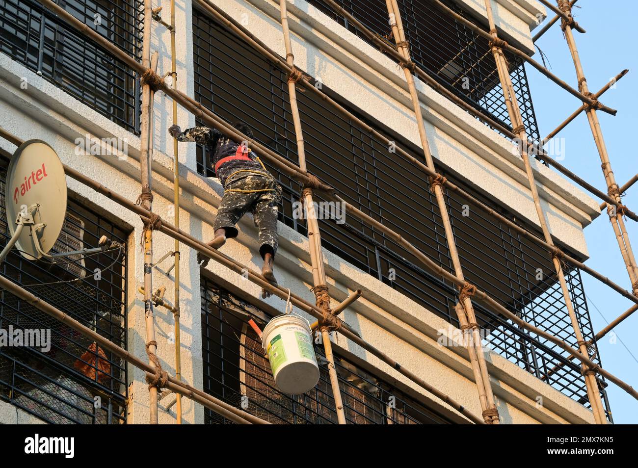 INDIA, Mumbai, apartment tower under renovation, bamboo scaffold, migrant worker from UP and Bihar doing paint works / INDIEN, Mumbai, Wohnhaus mit Baugerüst aus Bambus, Wanderarbeiter aus UP und Bihar bei Malerarbeiten Stock Photo