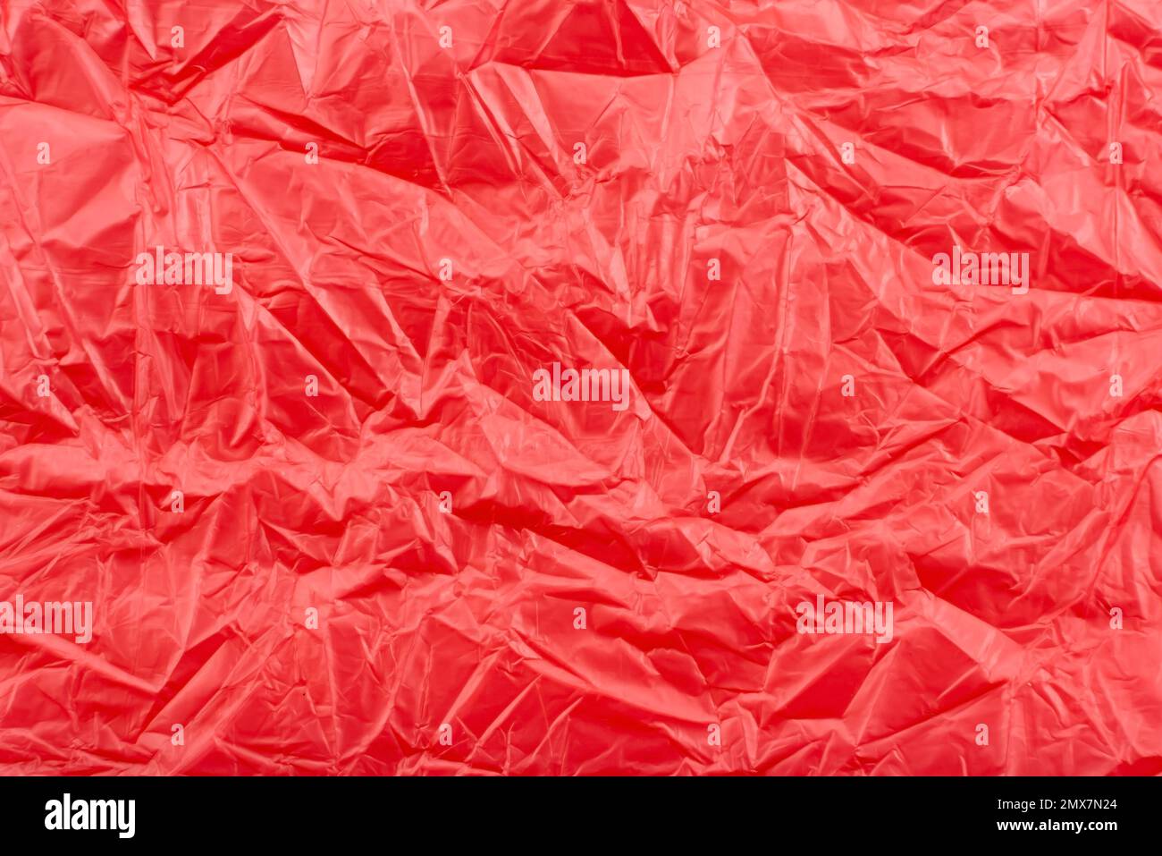 Texture of crumpled transparent polyethylene on a pink, red background, full frame Stock Photo
