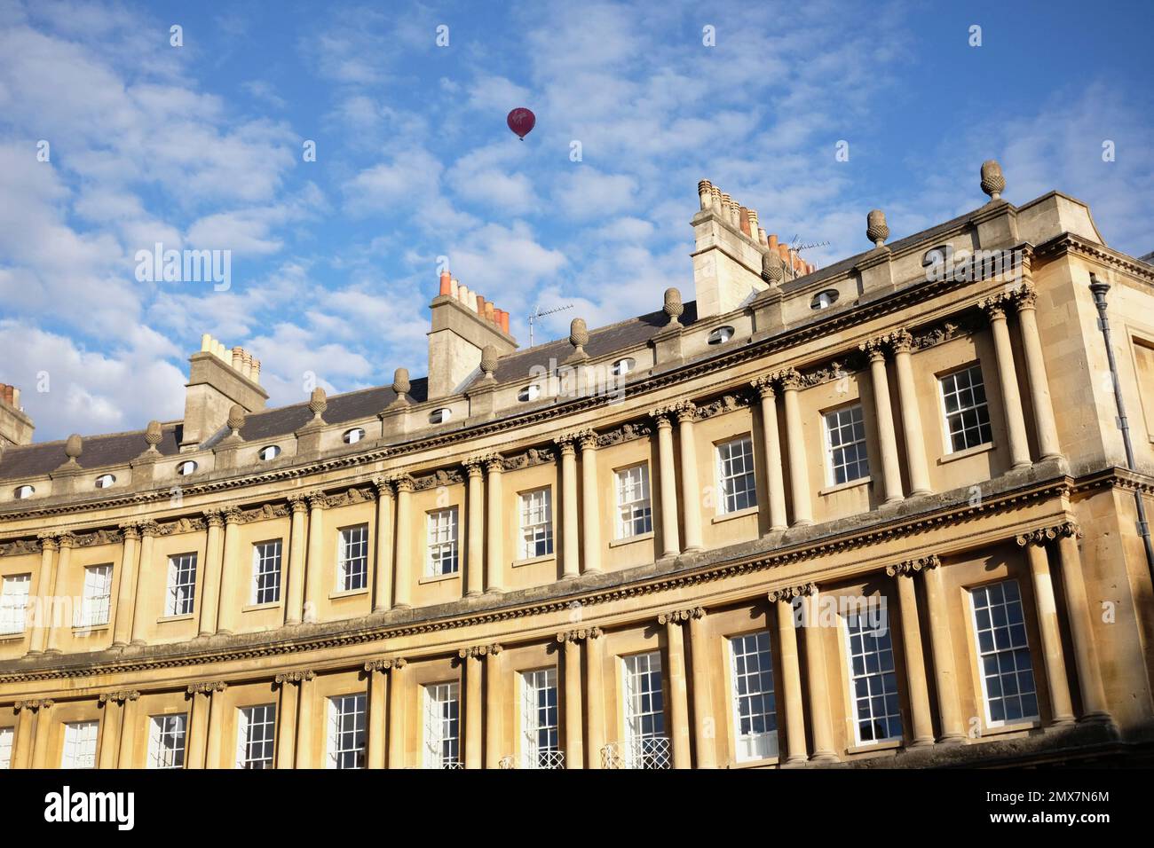 England, Bath, Exterior view of Royal Crescent with red hot air balloon in the blue sky with Cirrocumulus clouds. Stock Photo