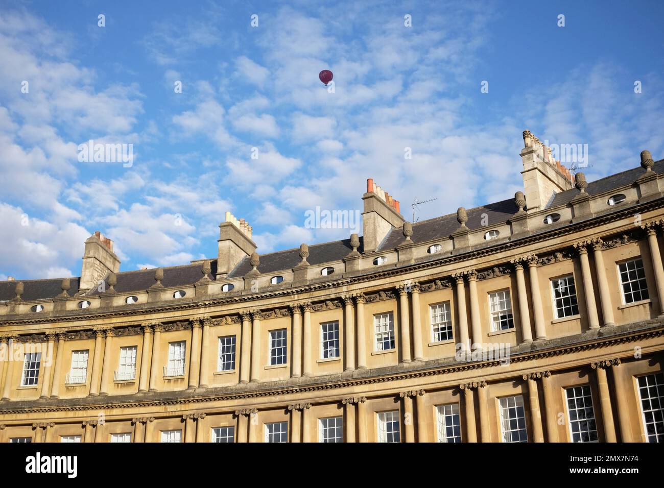 England, Bath, Exterior view of Royal Crescent with red hot air balloon in the blue sky with Cirrocumulus clouds. Stock Photo