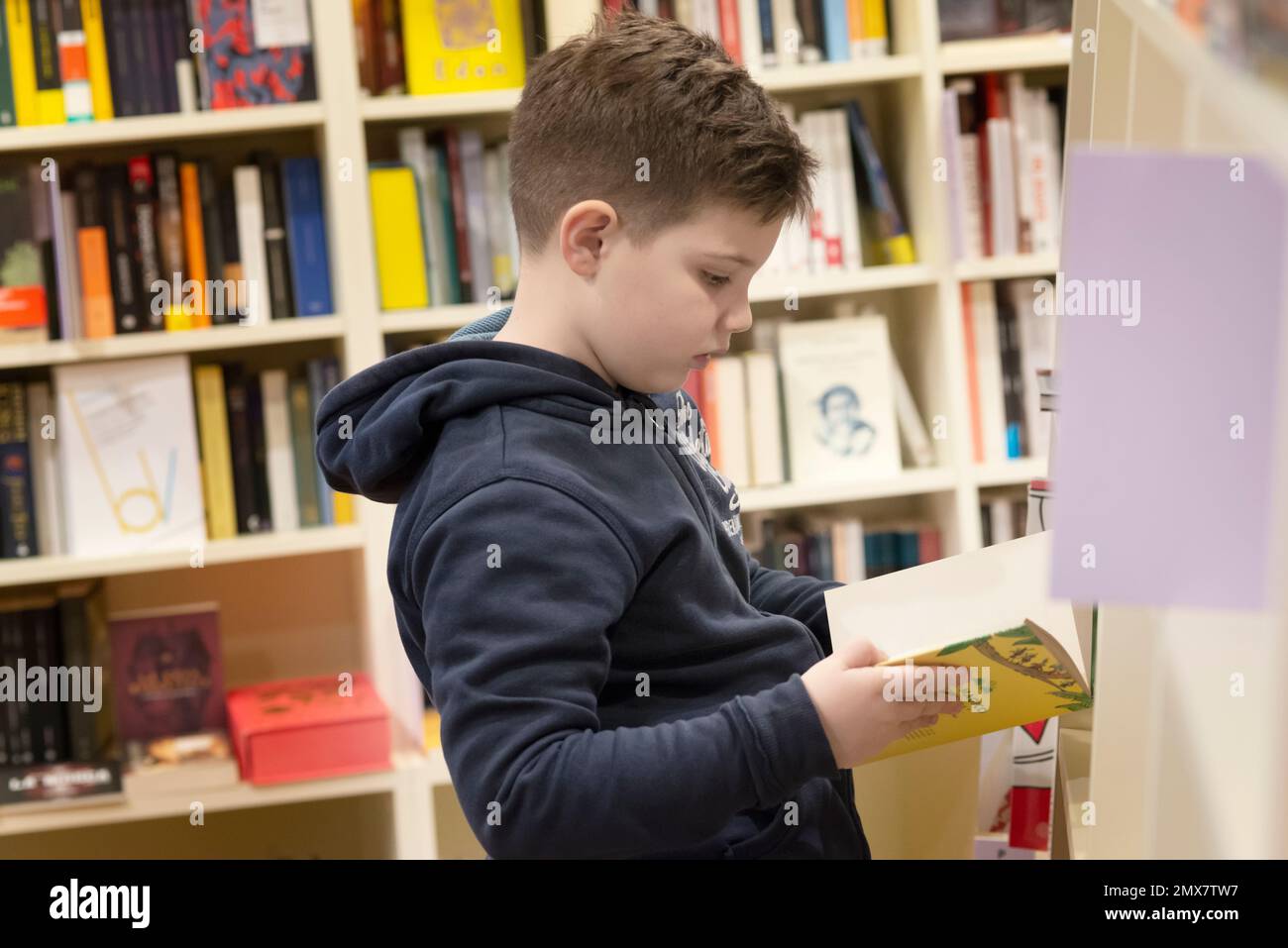 Boy Taking Book From Shelf in Bookstore Stock Photo