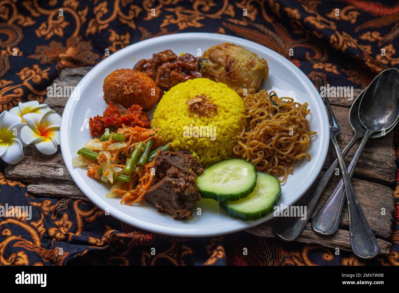 Indonesian traditional food, nasi kuning / yellow turmeric rice served with beef rendang, fried