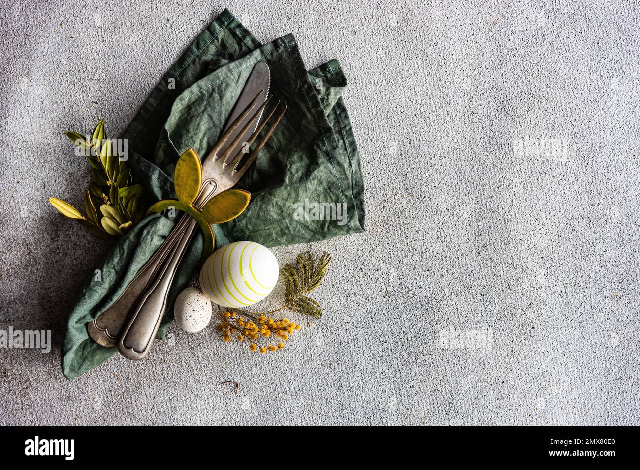 From above place setting for Easter dinner in green color on concrete background Stock Photo