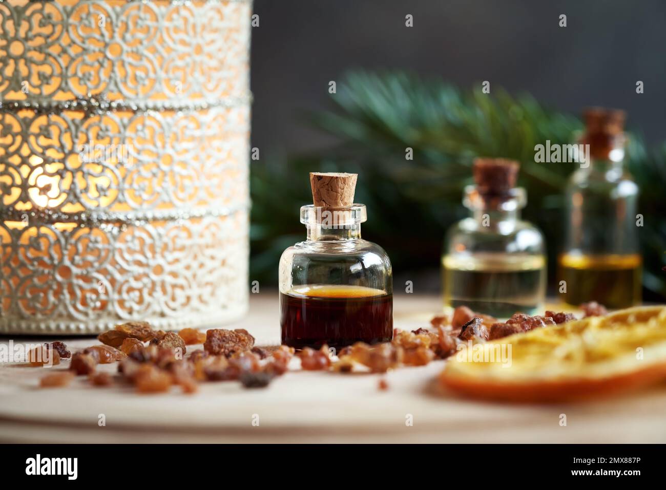 A bottle of myrrh essential oil with a candle and fir branches Stock Photo