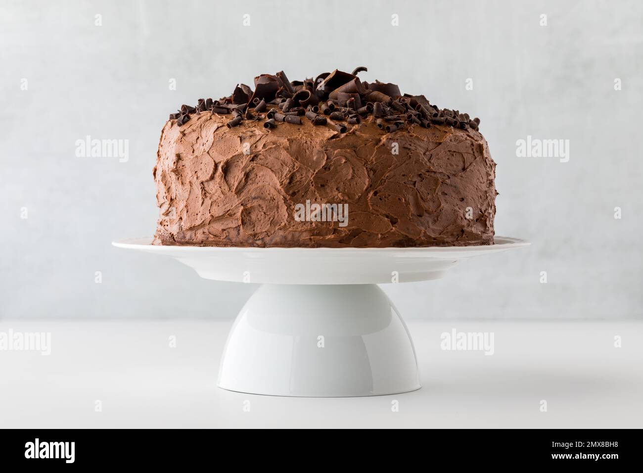Front facing view of a large chocolate cake decorated with chocolate curls. Stock Photo