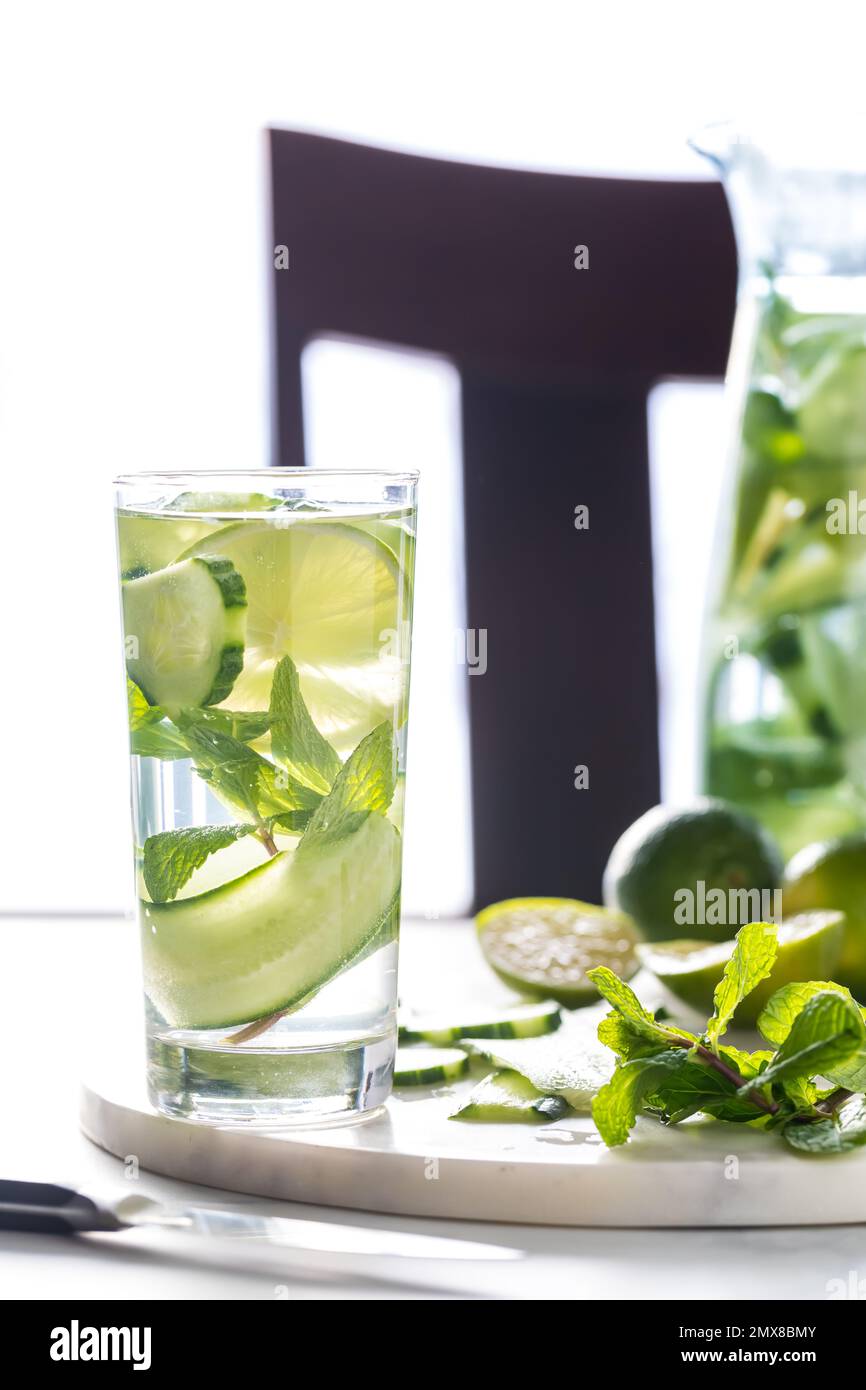 A tall glass of infused cucumber water with lime and mint leaves mixed in. Stock Photo