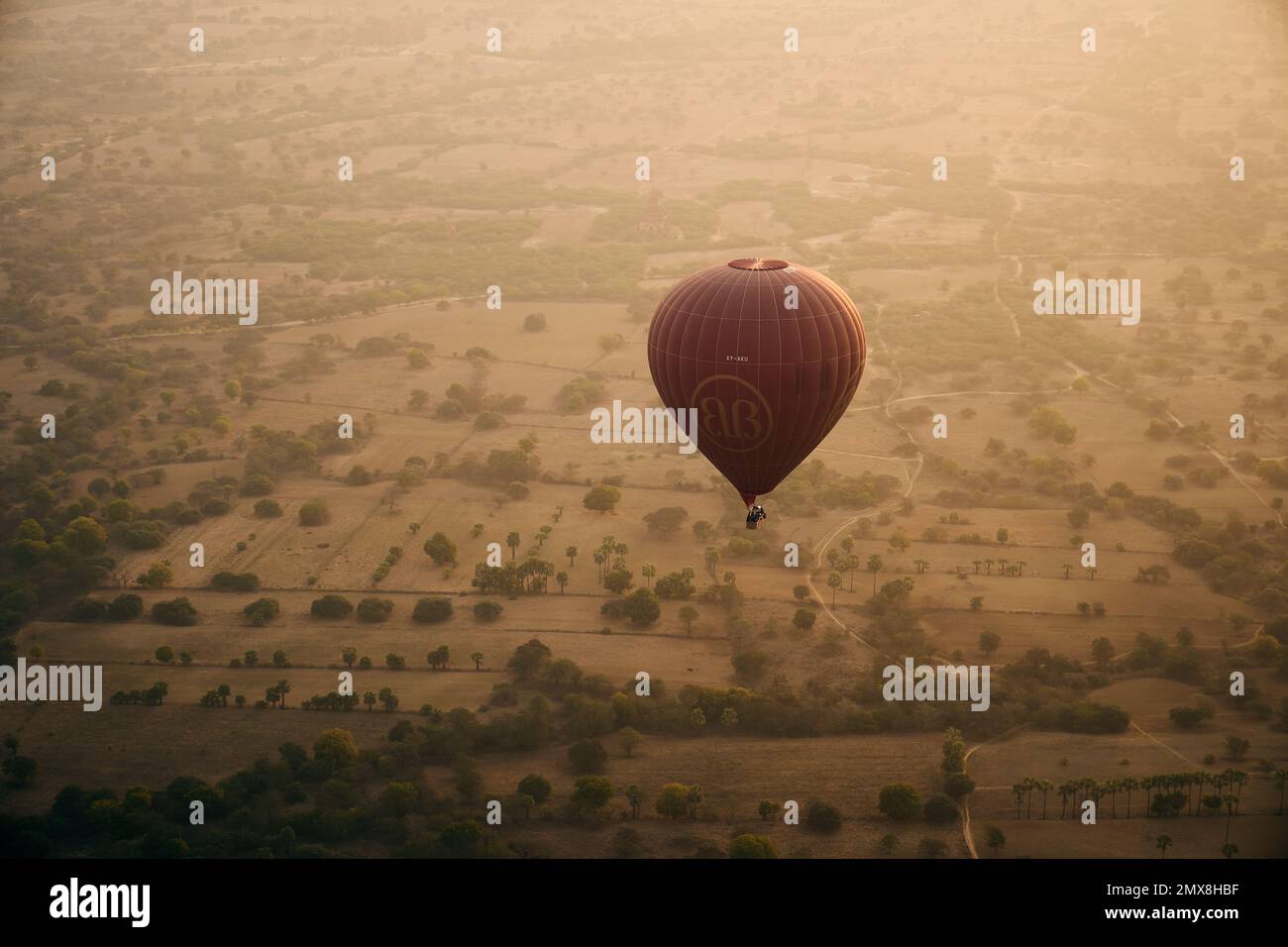Aerial view of a single hot air balloon flying over a cluster of Shan temples at sunrise in Bagan, Myanmar (Burma). Stock Photo
