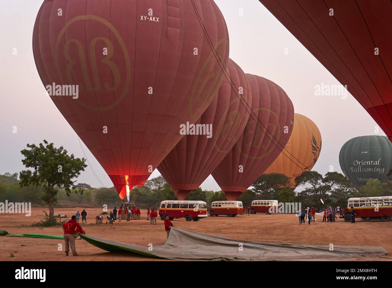 A group of red hot air balloons preparing to lift off at dawn near Bagan, Myanmar (Burma). Stock Photo