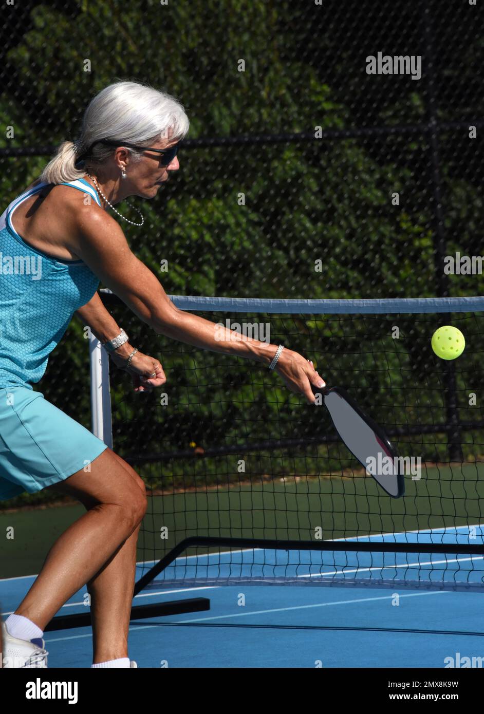 Closeup shows female pickle ball player's intense concentration during a match in Asheville, North Carolina.  She is a senior, and is wearing a turquo Stock Photo