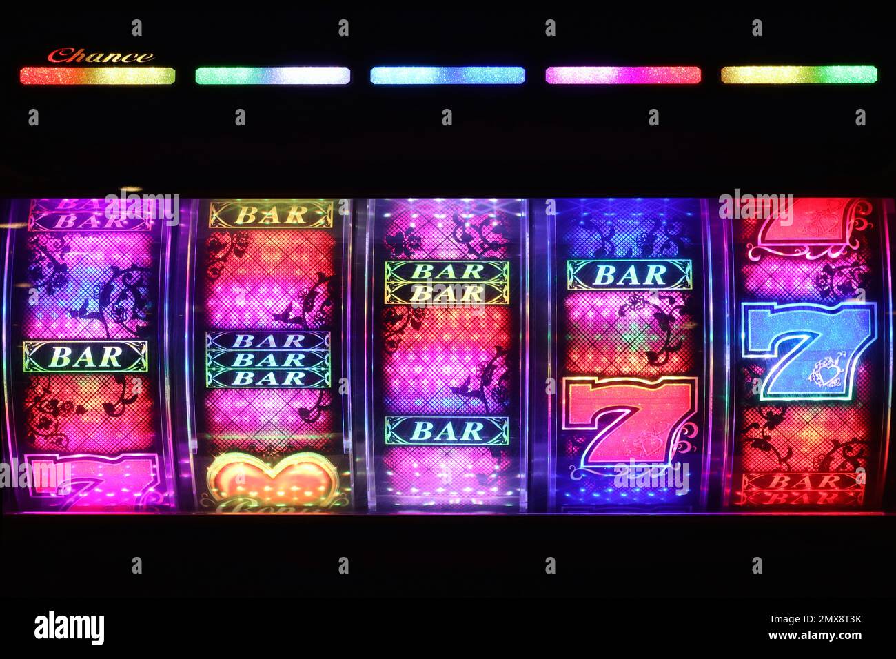 Illuminated slot machine drums with colourful graphics and flashing light sequences attract punters to pit their wits in amusement arcades. Stock Photo