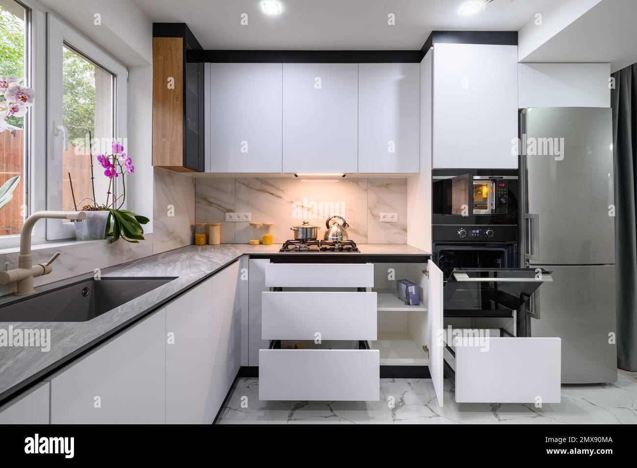 A spacious and updated kitchen with a white color scheme, a marble