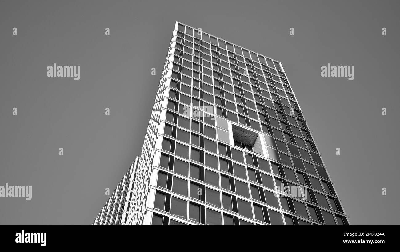 Commercial building close up in blue tone. Gigantic skyscraper from below. Architecture details of modern building amd glass facade. Black and white. Stock Photo