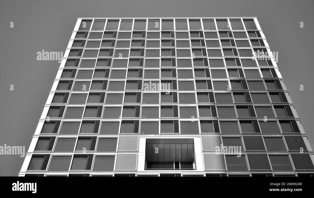 Commercial building close up in blue tone. Gigantic skyscraper from below. Architecture details of modern building amd glass facade. Black and white. Stock Photo