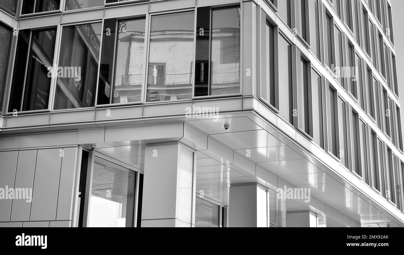 Commercial building close up in blue tone. Gigantic skyscraper from below. Architecture details of modern building amd glass facade. Black and white. Stock Photo