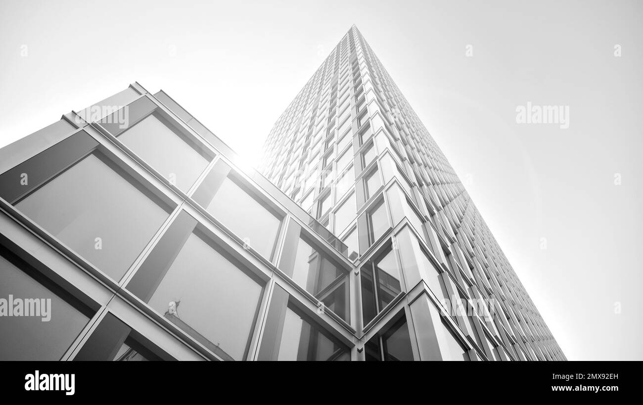 Commercial building close up in blue tone. Gigantic skyscraper from below. Architecture details of modern building amd glass facade. Black and white. Stock Photo