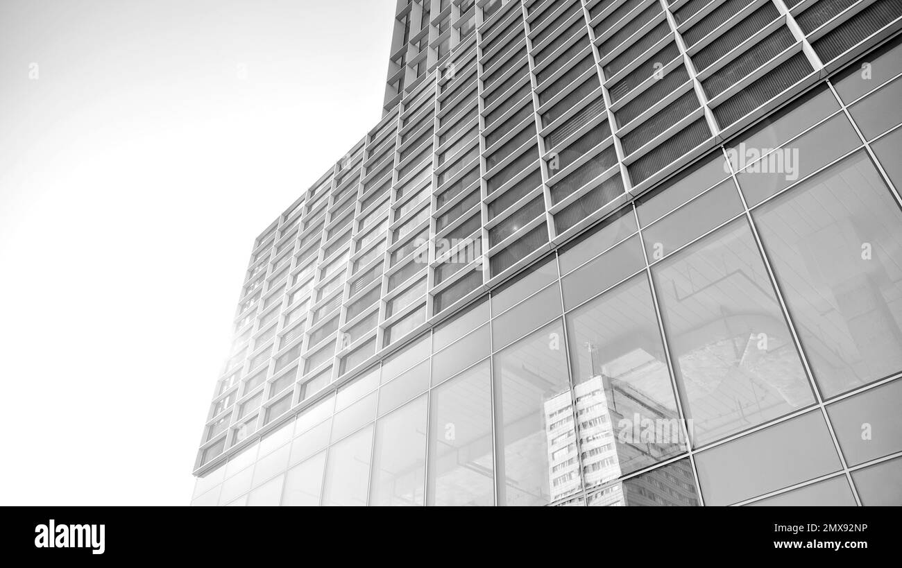 Commercial building close up in blue tone. Gigantic skyscraper from below. Architecture details of modern building amd glass facade. Black and white. Stock Photo