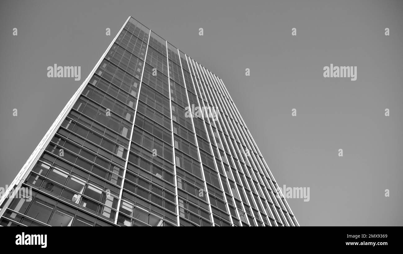 Commercial building close up in blue tone. Gigantic skyscraper from below. Architecture details of modern building amd glass facade. Black and white. Stock Photo
