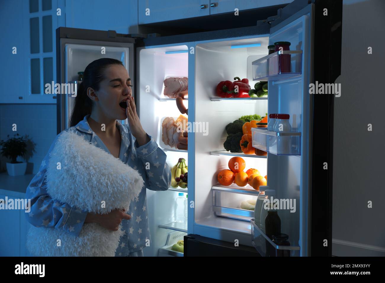 https://c8.alamy.com/comp/2MX93YY/young-woman-with-pillow-near-open-refrigerator-at-night-2MX93YY.jpg