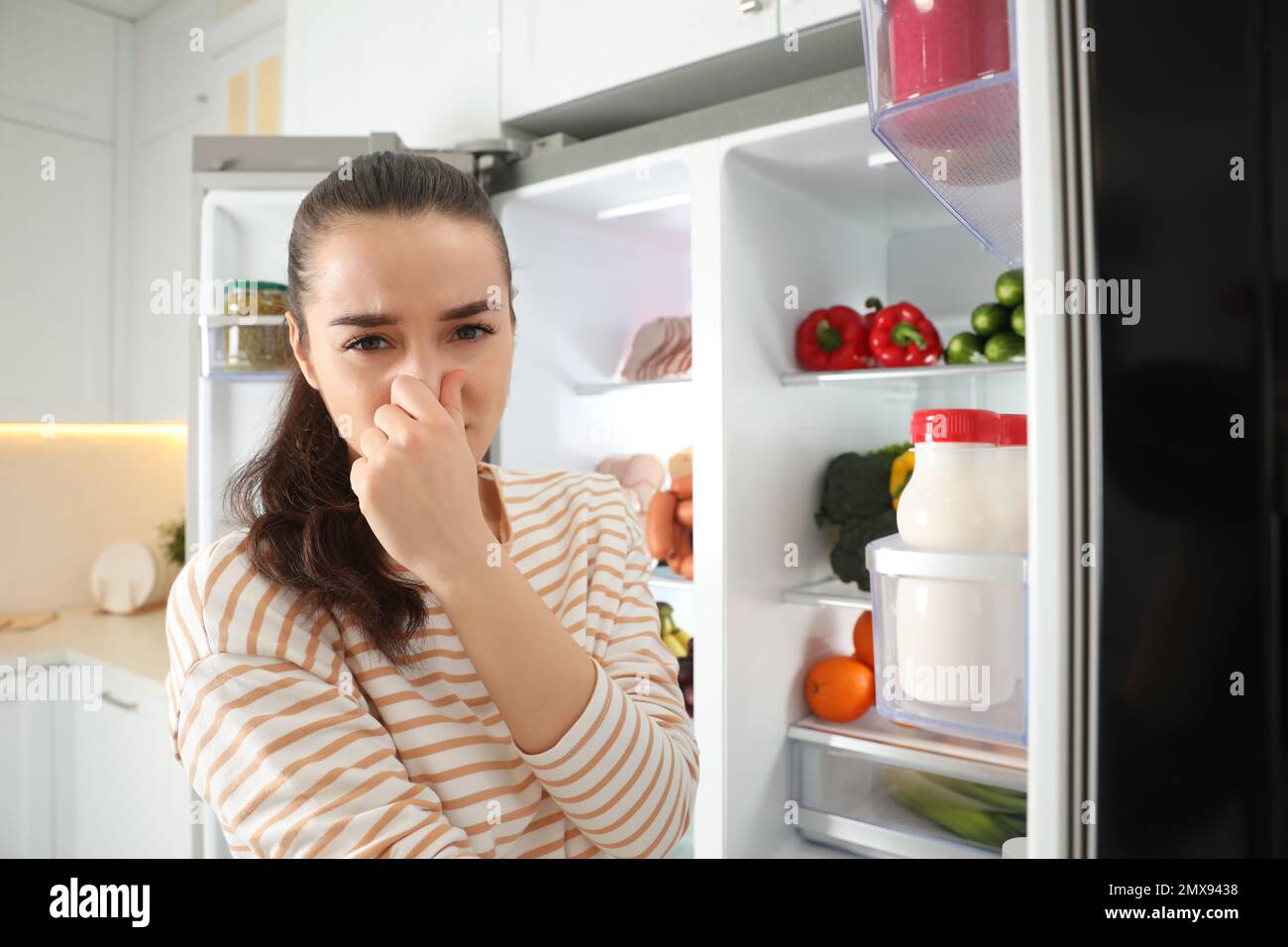 Young woman holding nose cause of bad smell in refrigerator in kitchen Stock Photo Alamy