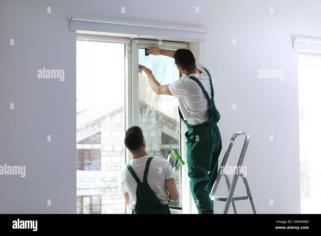 Professional workers tinting window with foil indoors Stock Photo