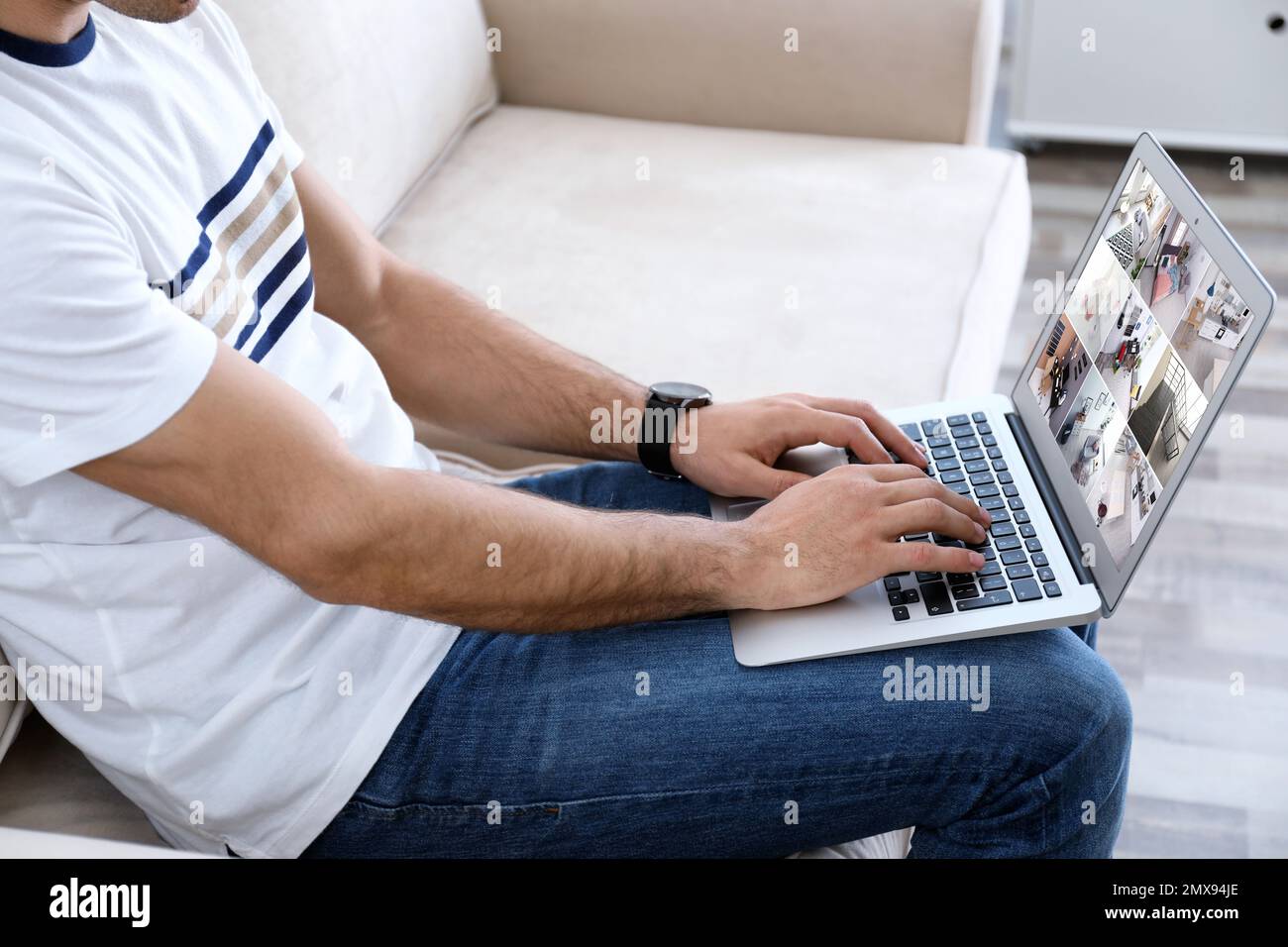 Man monitoring modern cctv cameras on laptop indoors, closeup. Home