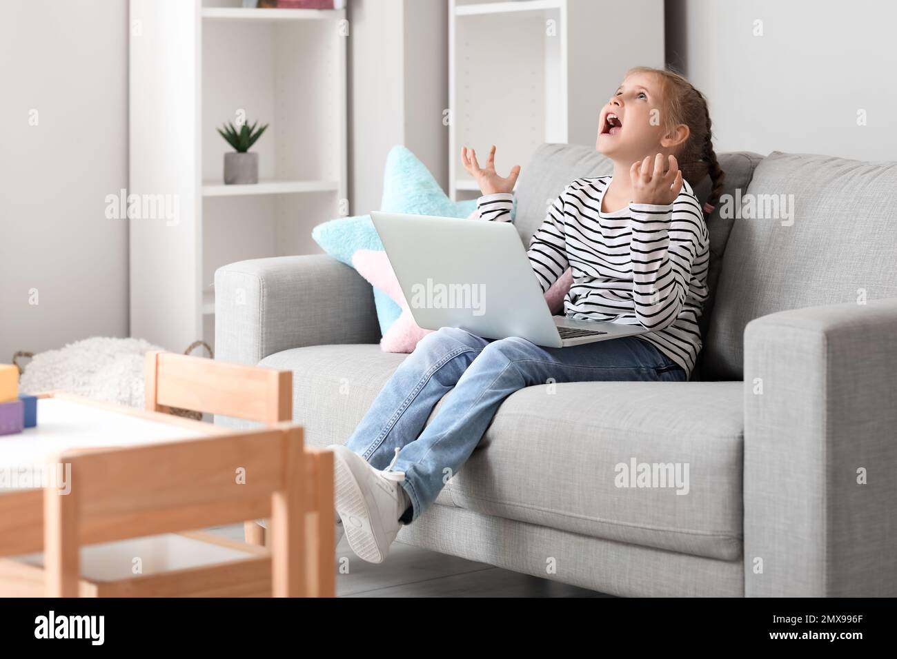 Angry little girl video chatting with psychologist on laptop at home Stock Photo