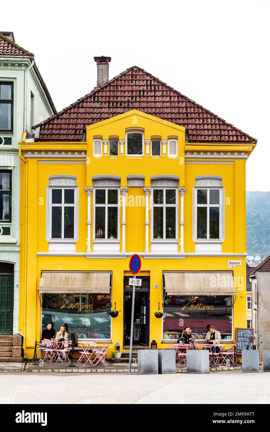 People eating al fresco and yellow exterior of Løvetann Café & Bistro, Nordnes, Bergen, Norway Stock Photo