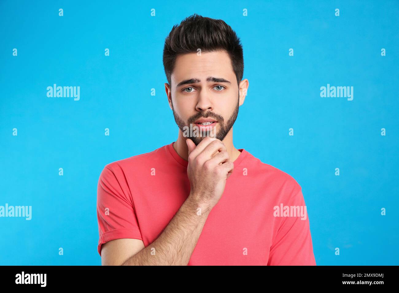 Pensive young man on light blue background. Thinking about difficult ...