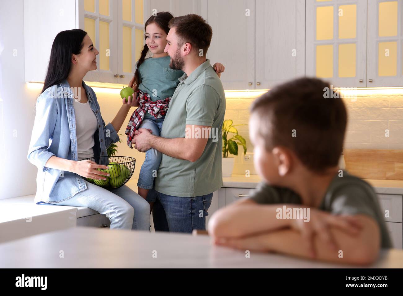 Unhappy little boy feeling jealous while parents spending time with his